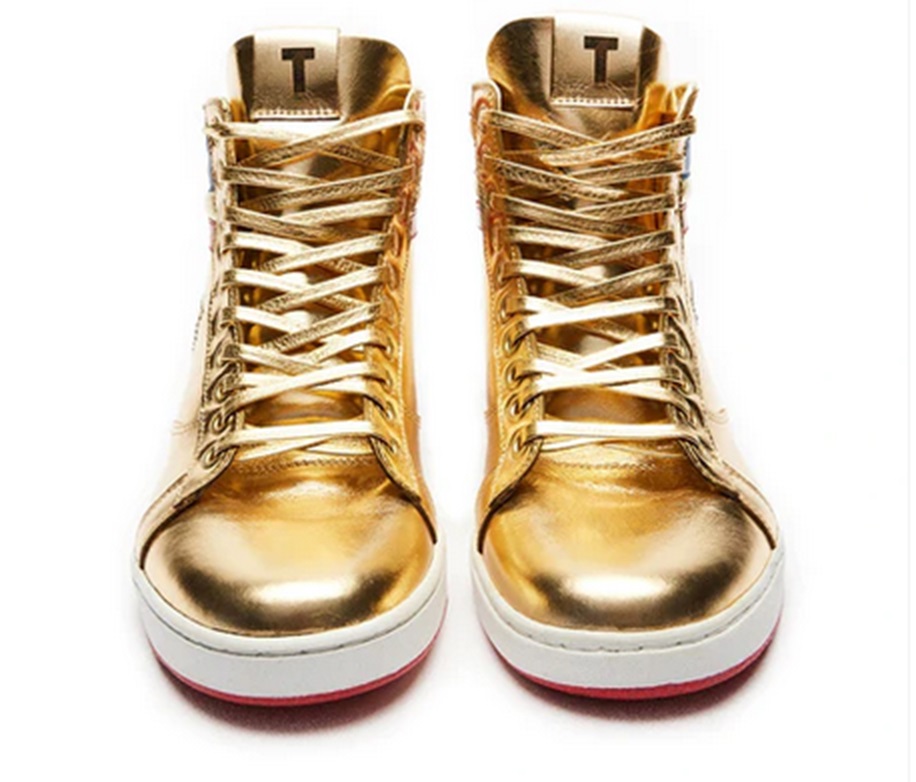 Shiny gold baseball boots with a T on the tongue